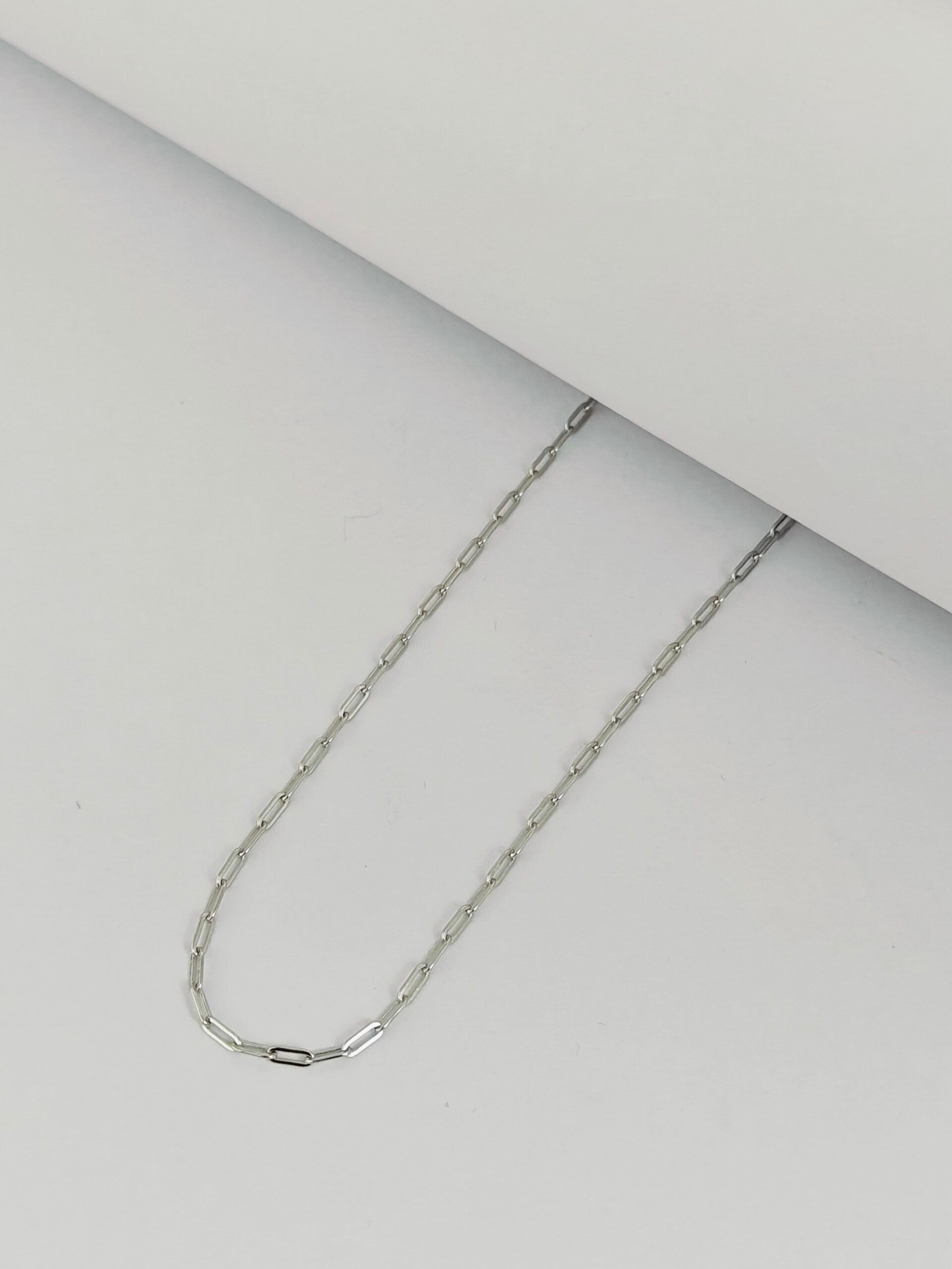 Silver chain necklace on a light gray surface